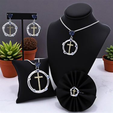 Jewelry set with cross designs on a black stand with potted plants in the background